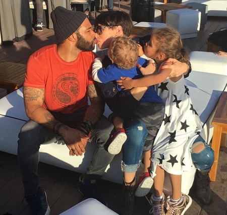 Jennifer Pfautch kissing her husband Omari Hardwick with her two children